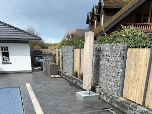 Ein moderner Außenbereich mit Holzzaun und grauen Pflastersteinen bei bewölktem Himmel.