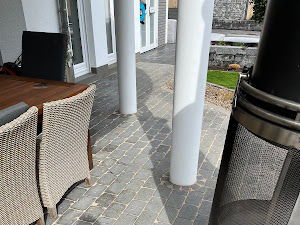 Säulen auf Terrasse mit geflochtenen Stühlen und Kamin in elegantem, modernem Design.