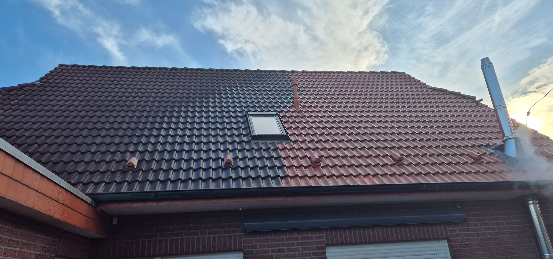 Das Dach eines Hauses mit einem kleinen Fenster und unterschiedlich gefärbten Ziegeln