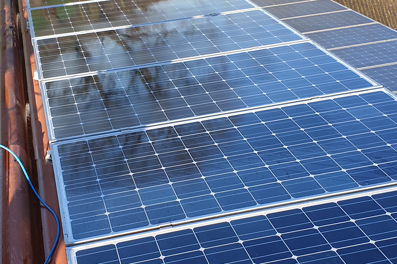 Mehrere glänzende blaue Solarpaneele sind ordentlich auf einem Dach installiert