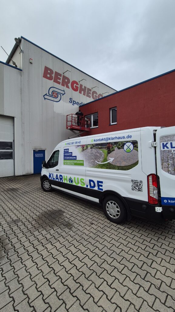 Ein weißer Transporter mit Klarhaus Logo steht vor einer Halle mit roter Fassade