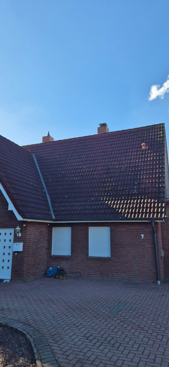 Ein rotes Backsteinhaus mit dunklem Dach und blauen Himmel im Hintergrund