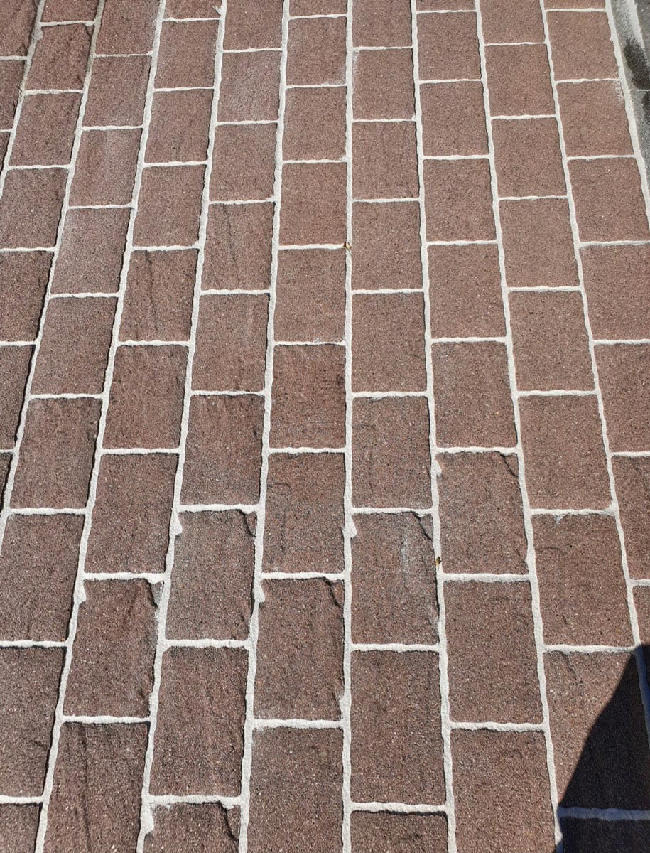 Rote Backsteinpflastersteine mit weißen Fugen in ordentlichen Reihen angeordnet