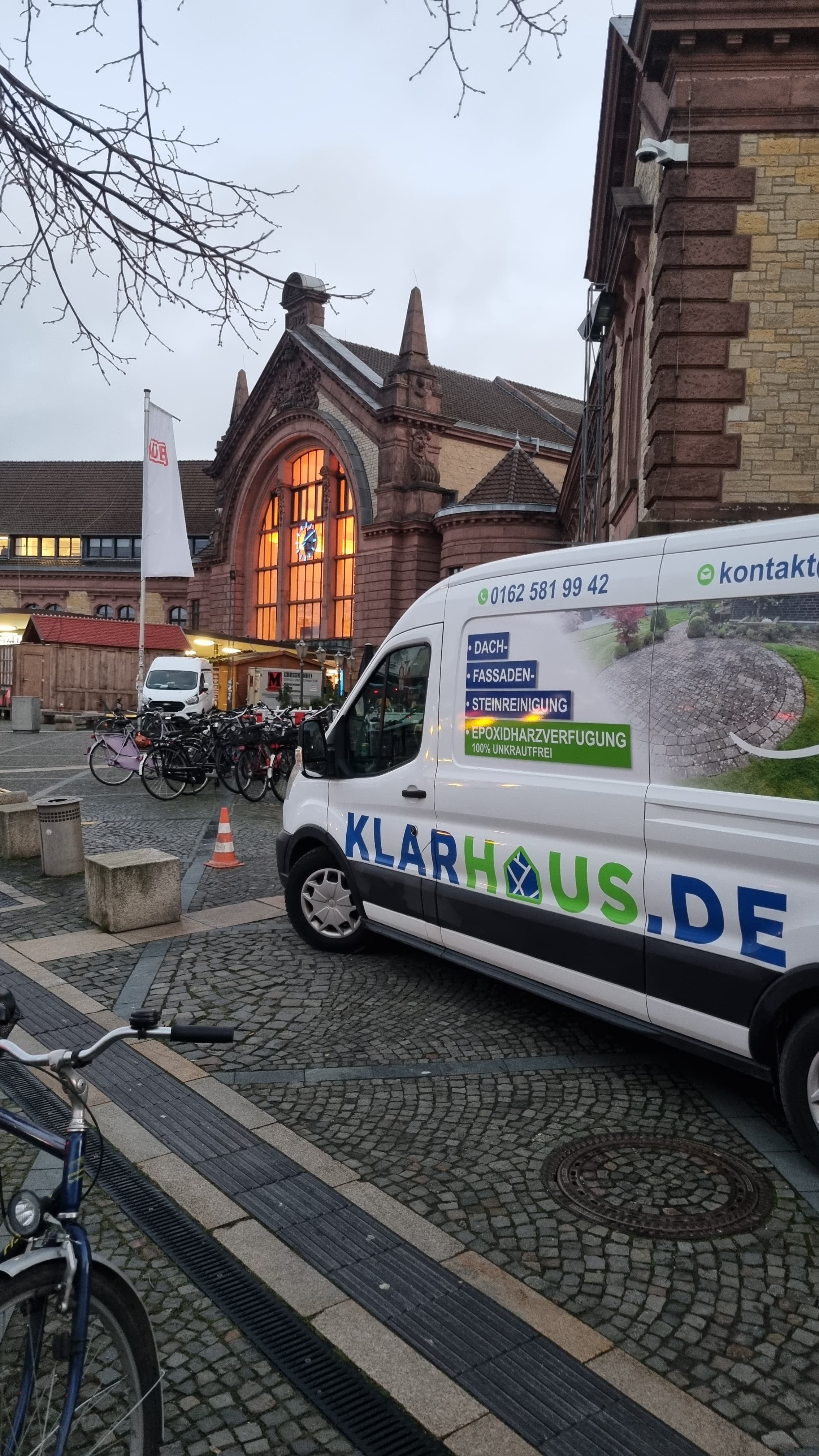 Ein Klarhausde Transporter steht vor einem historischen Gebäude mit leuchtenden Fenstern